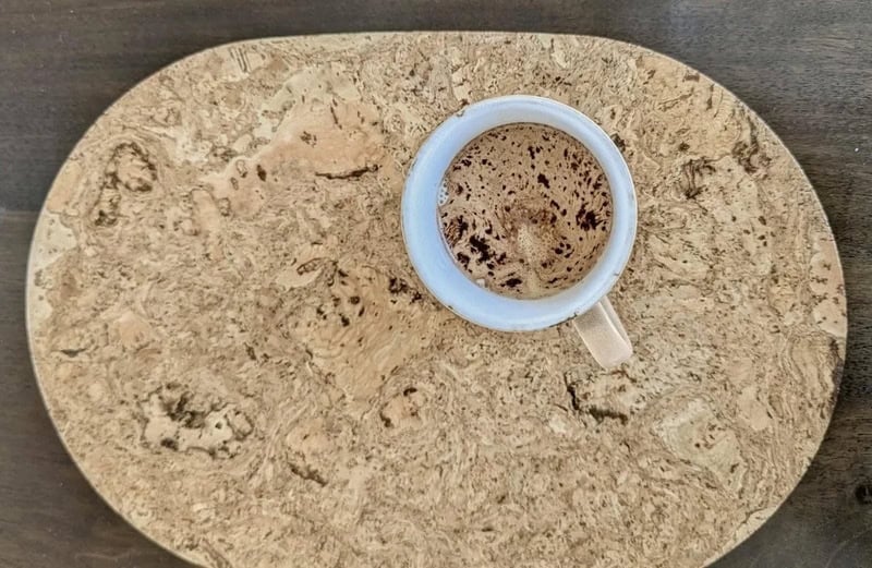 Coffee cup on a round stone serving tray with a wooden surface.