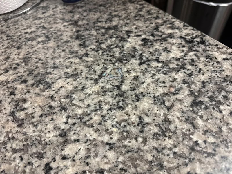 Close-up of a granite countertop with a small, shiny object in the center.