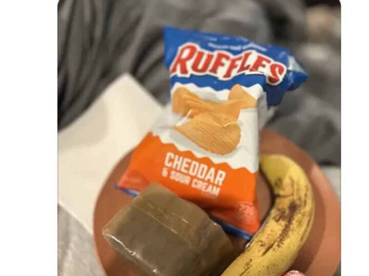 Charcuterie board with Ruffles Cheddar chips, banana, lollipop, and a small block of cheese.
