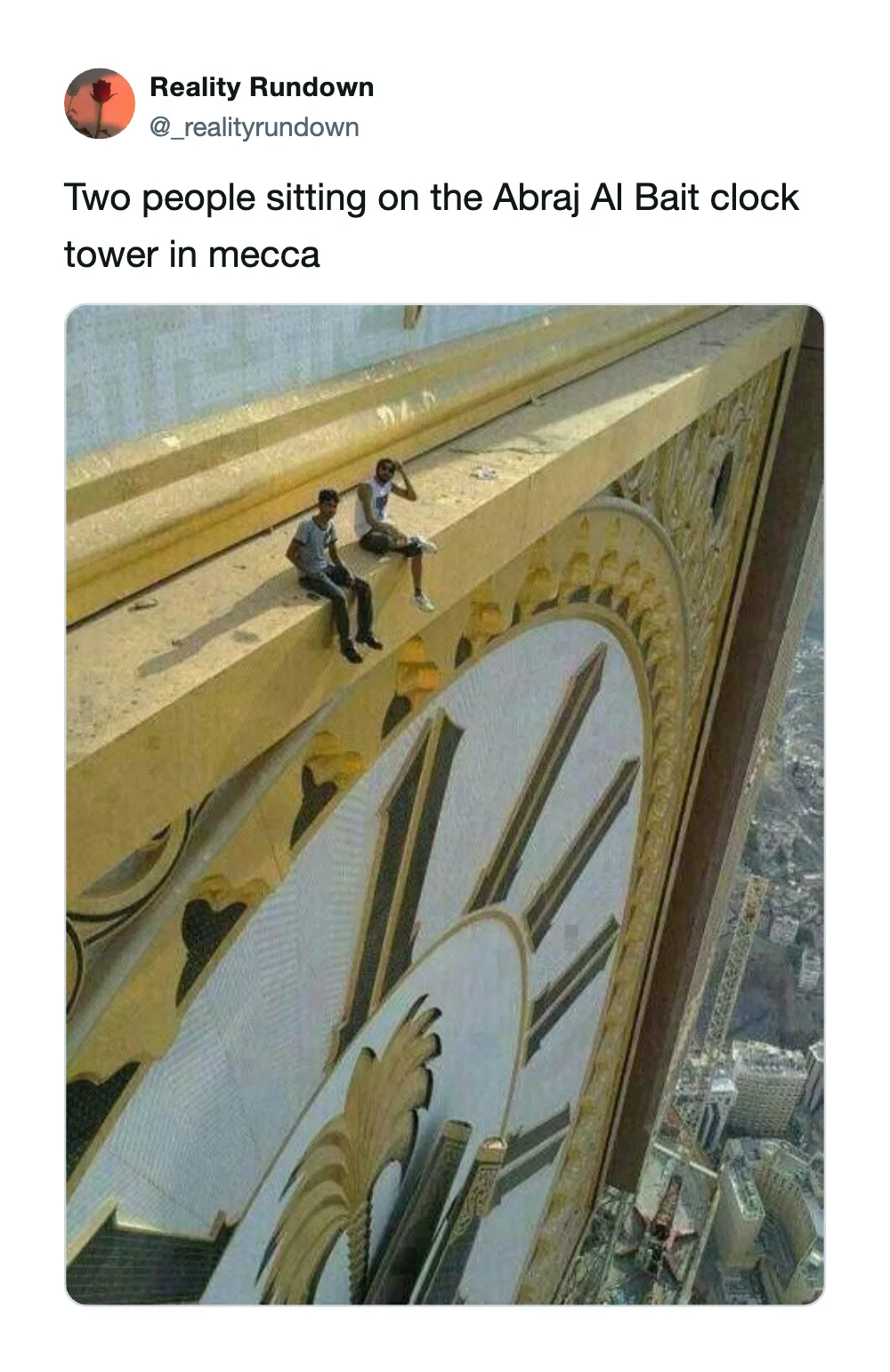 Two people sitting on the Abraj Al Bait clock tower in Mecca.