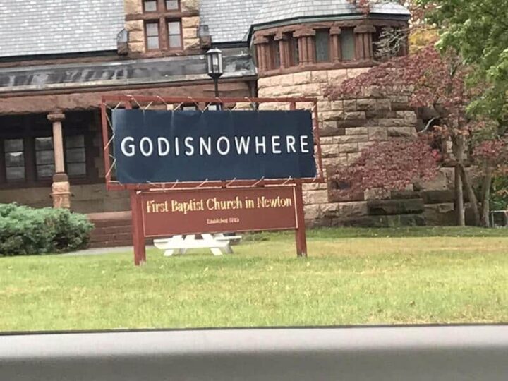 Sign for First Baptist Church in Newton with 'GODISNOWHERE' on a billboard.