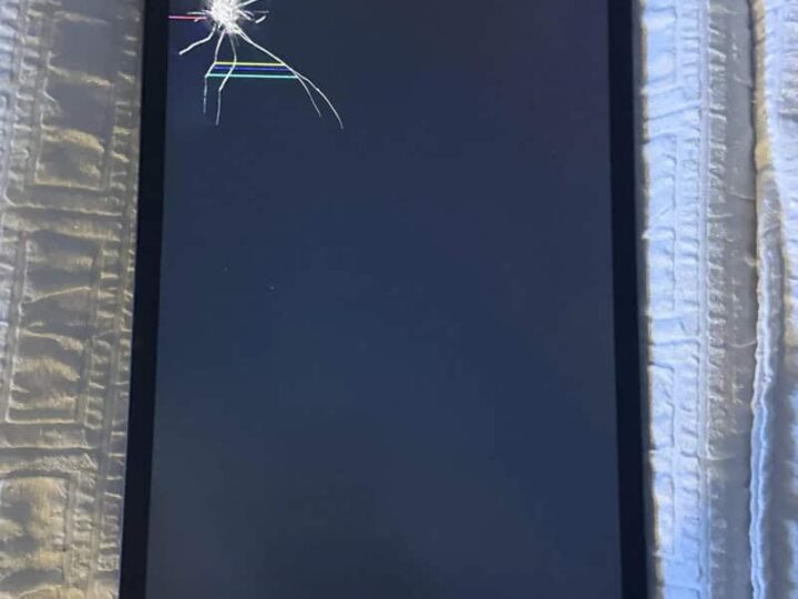 Tablet with a cracked screen on a white textured surface.