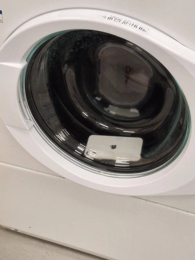 Washing machine with a phone inside the drum, showing a humorous fail.
