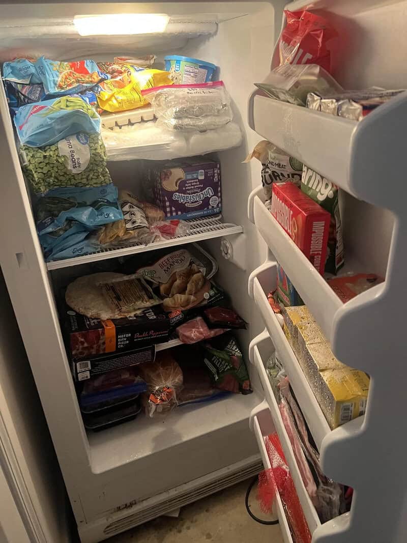 Open fridge with various food items and snacks inside.
