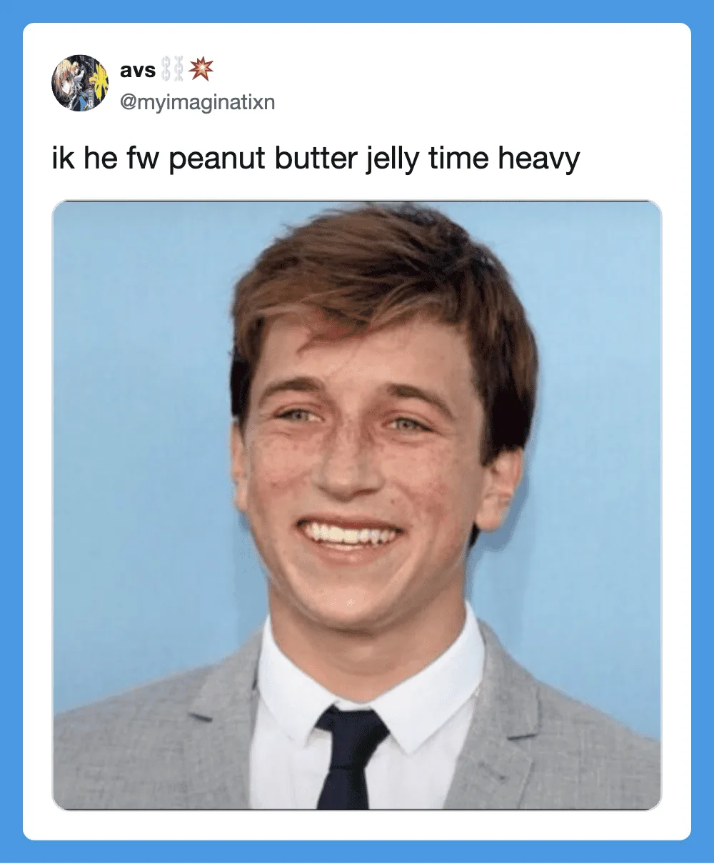 Smiling young man in a gray suit with a blue background.