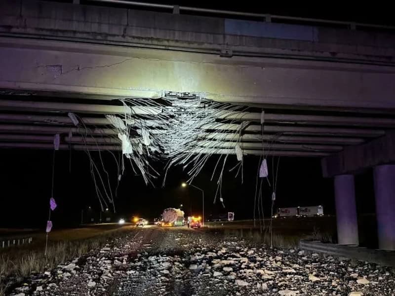 Bridge damaged with hanging debris and broken concrete, night scene.
