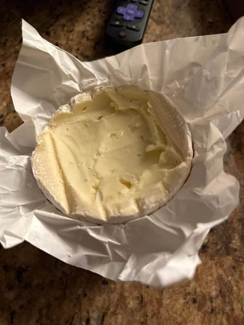Empty ice cream container with some remaining ice cream and a remote control nearby.