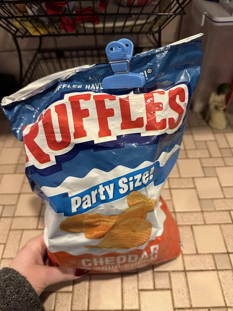 Bag of Ruffles party size potato chips with a blue clip on top.