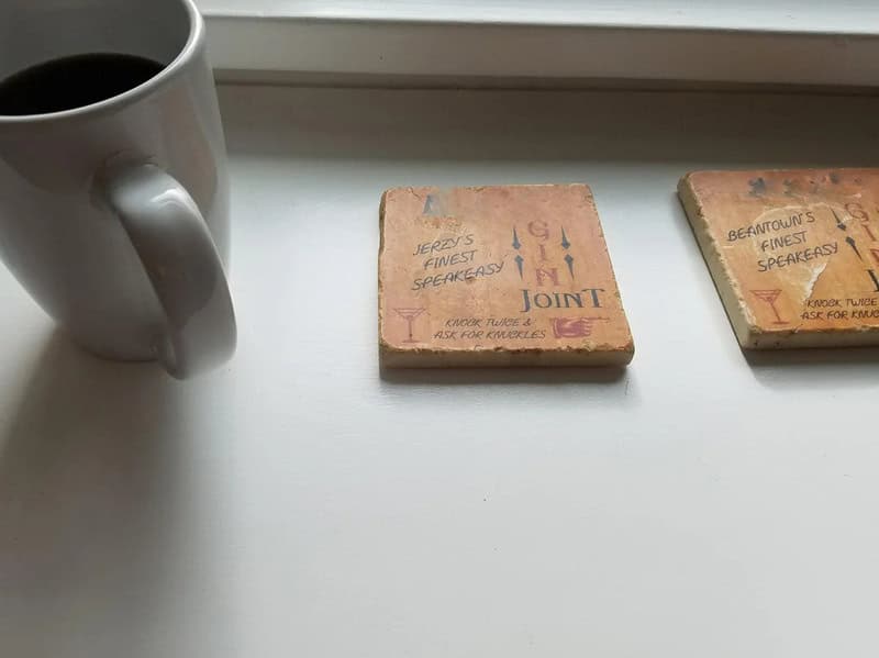 Coffee mug and two vintage Scrabble tiles on a windowsill.